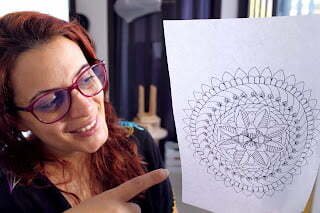 this is the image of a woman holding a mandala sketch