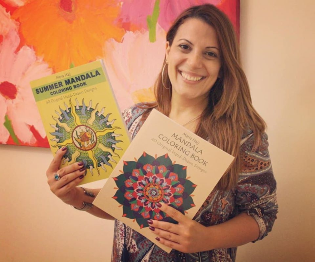 a woman smiling while holding two mandala coloring books