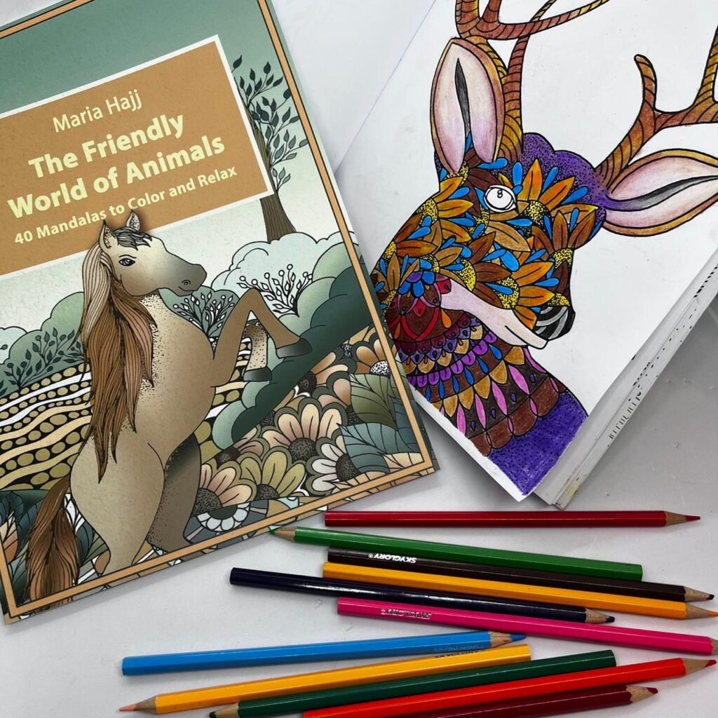 a mandala coloring book and another coloring book open with a colored image and wooden coloring pencils