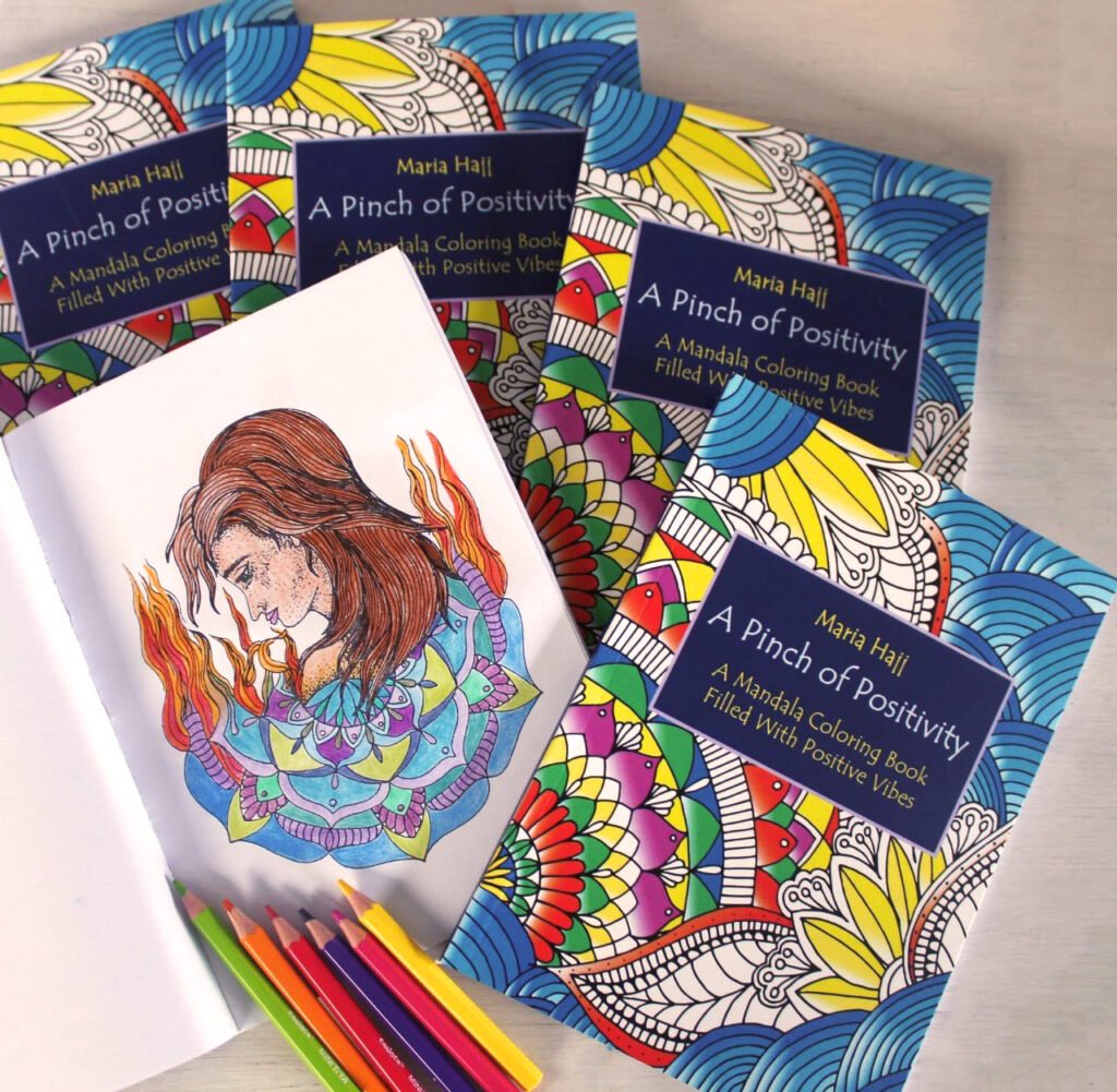 a pile of mandala coloring books with one open colored page